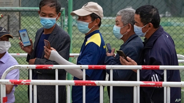 마스크를 쓴 중국 베이징 시민들이 지난 6월 시노팜 백신 접종을 위해 줄을 선 채로 자신의 건강코드를 확인하고 있다. 사진=AP/연합