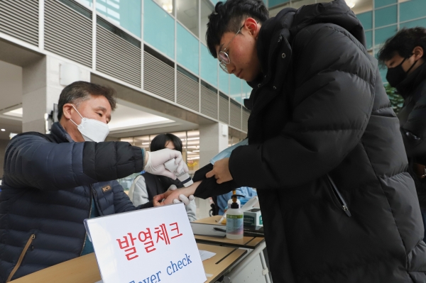 인하대 정석학술정보관 담당자들이 21일 도서관에 입장하는 학생들의 열을 확인하고 있다.